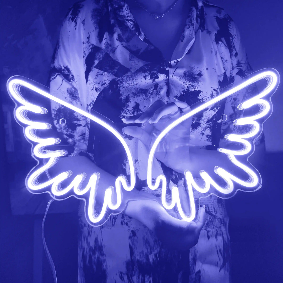 A girl holding a custom neon sign of blue color in the shape of angel wings | ManhattanNeons