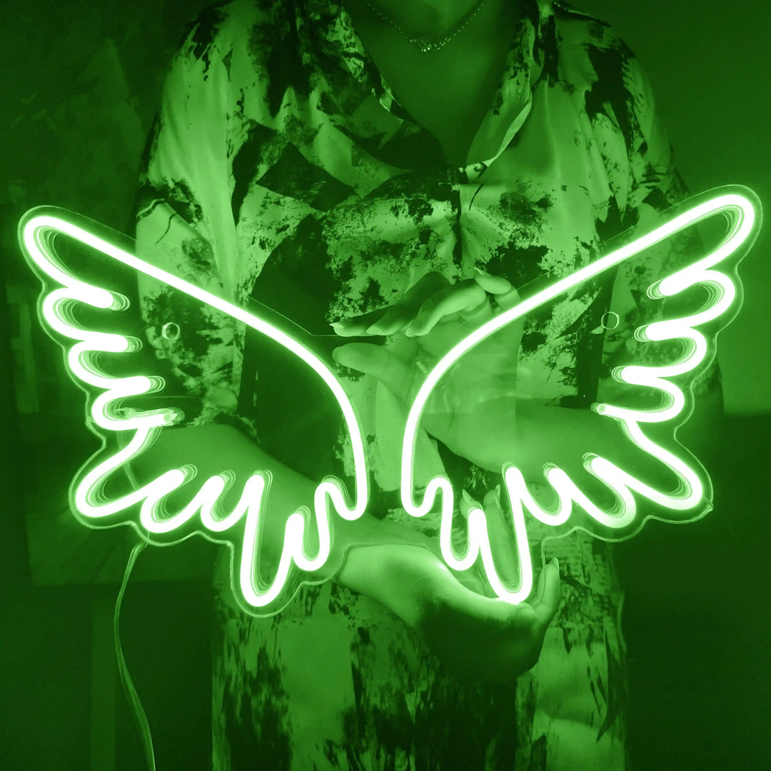 A girl holding a custom neon sign of green color in the shape of angel wings | ManhattanNeons