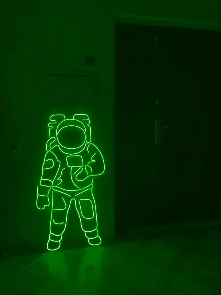 Green colored Astronaut LED Neon Sign placed on the floor beside a door - from manhattonneons.com.