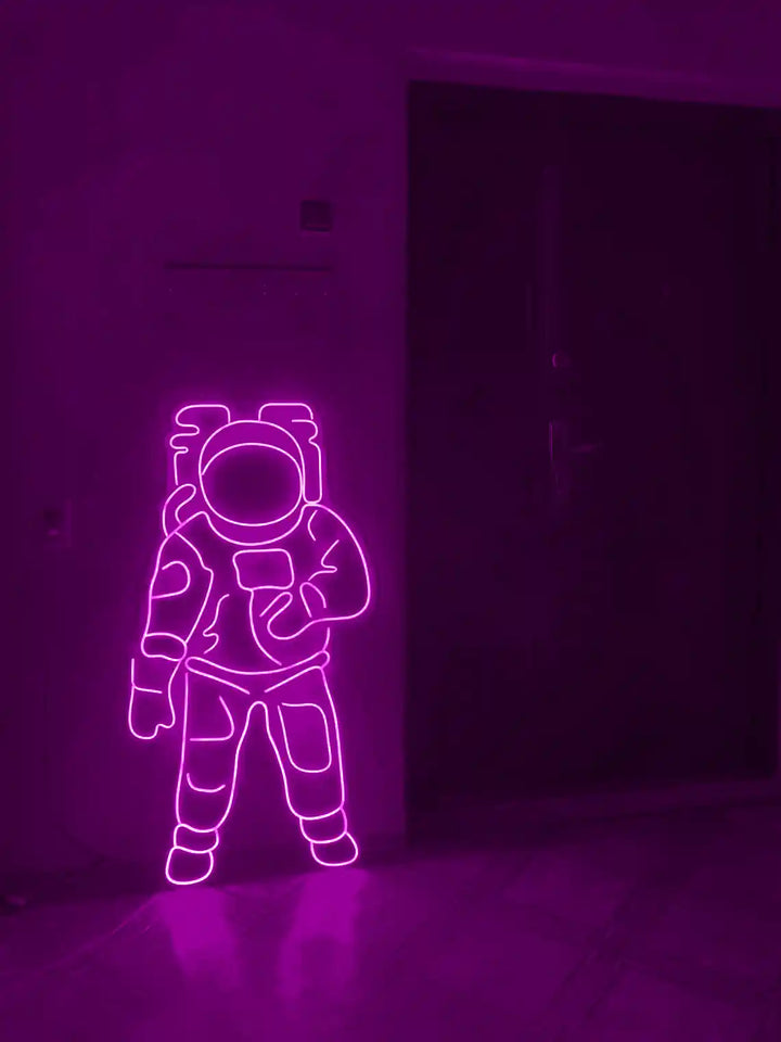 Purple colored Astronaut LED Neon Sign placed on the floor beside a door - from manhattonneons.com.