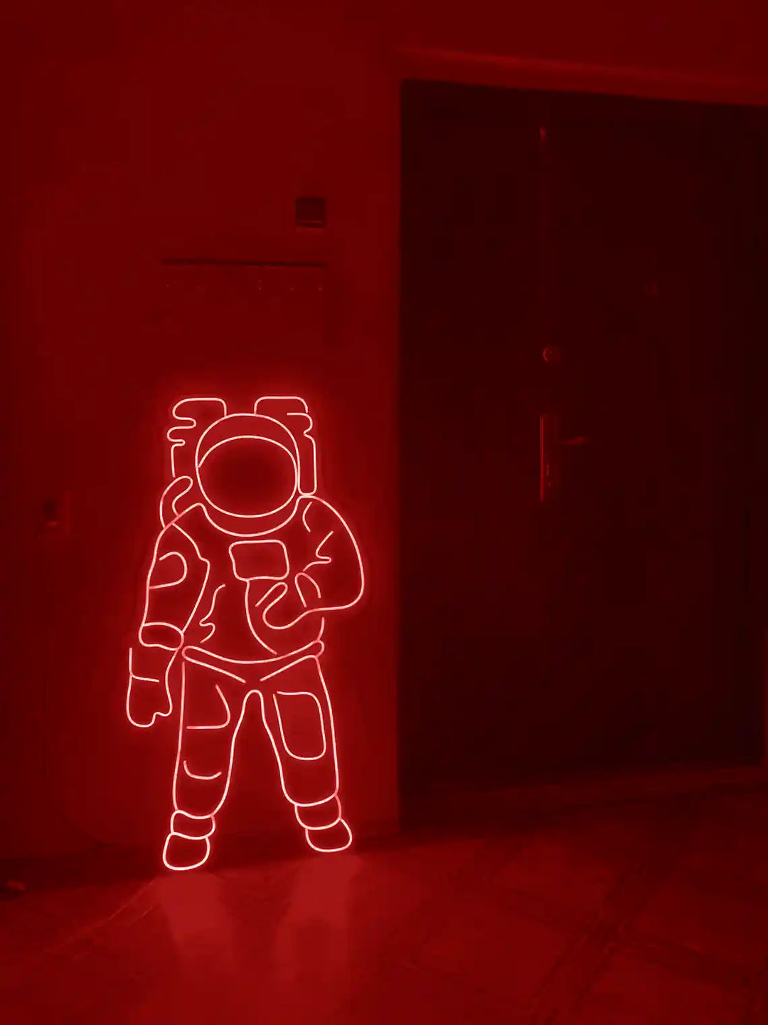 Red colored Astronaut LED Neon Sign placed on the floor beside a door - from manhattonneons.com.