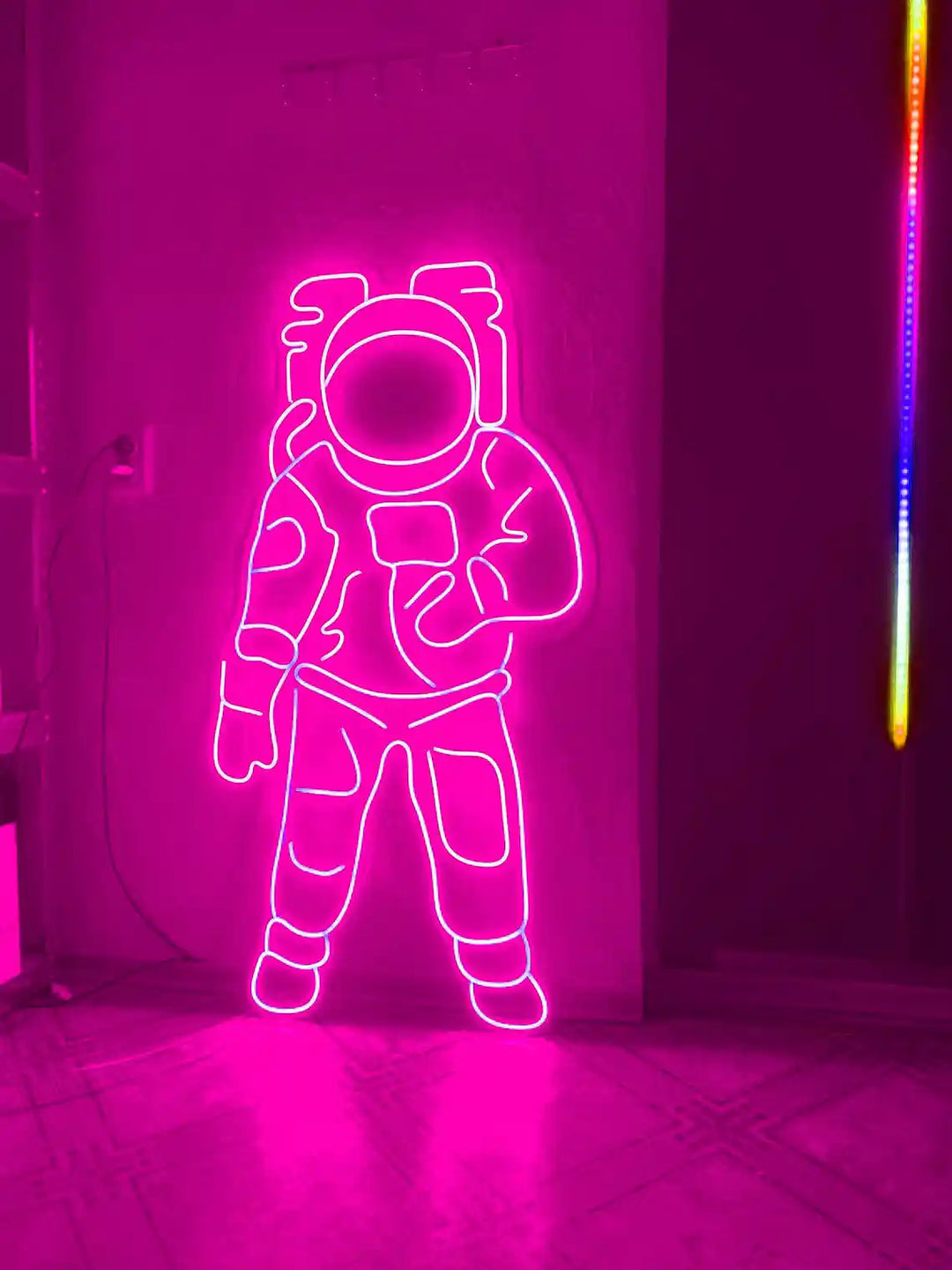 Pink colored Astronaut LED Neon Sign placed on the floor beside a door - from manhattonneons.com.